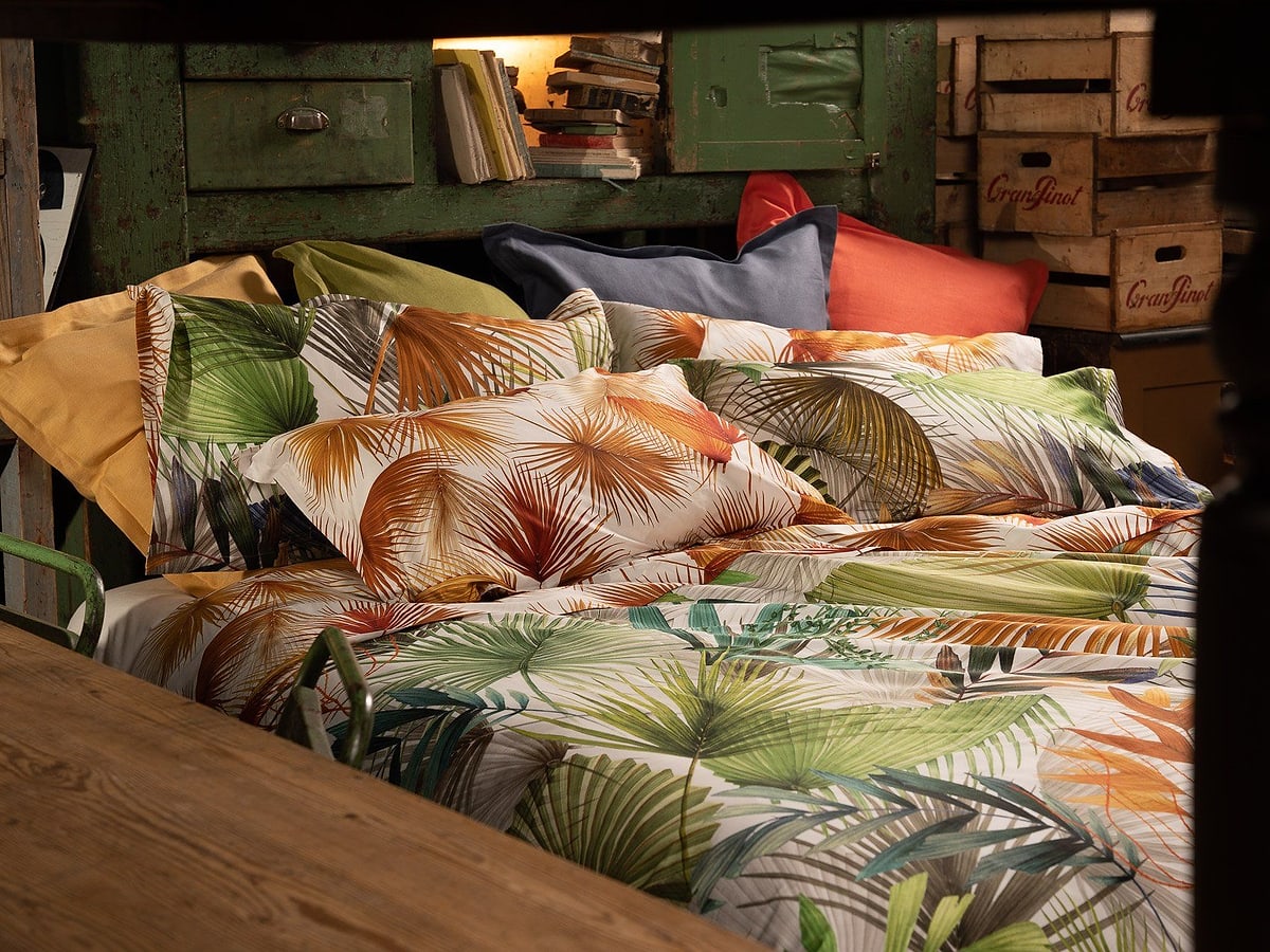 Completo letto a stampa tropicale in una camera dai toni caldi