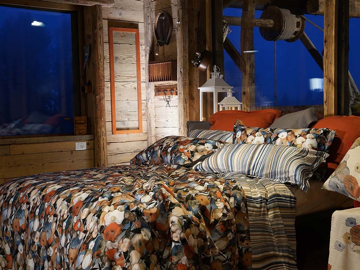 Completo letto a righe e fantasia in una camera rivestita in legno
