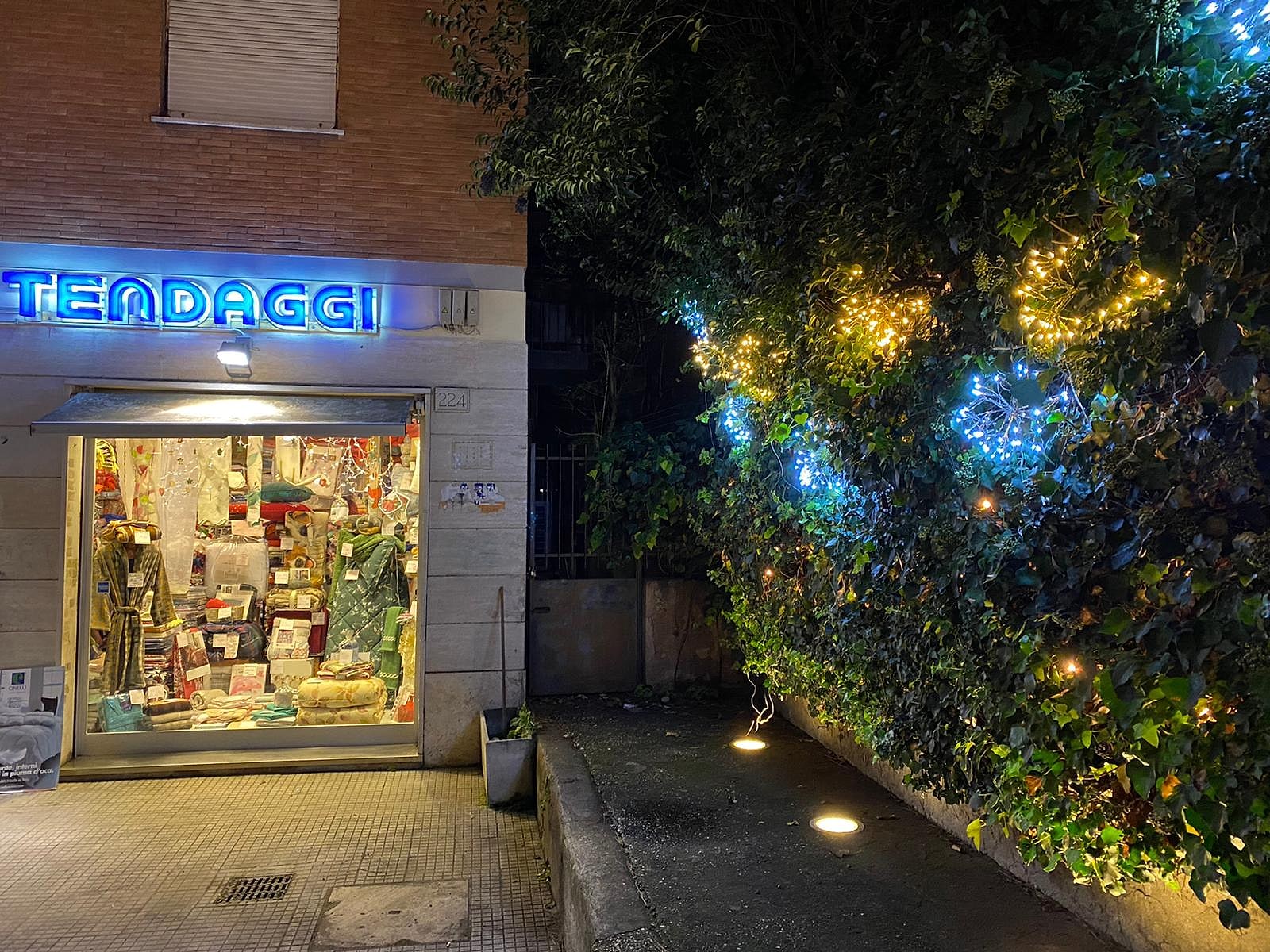 La vetrina di Stevin 90 in via di Bravetta, con l'insegna TENDAGGI illuminata di sera