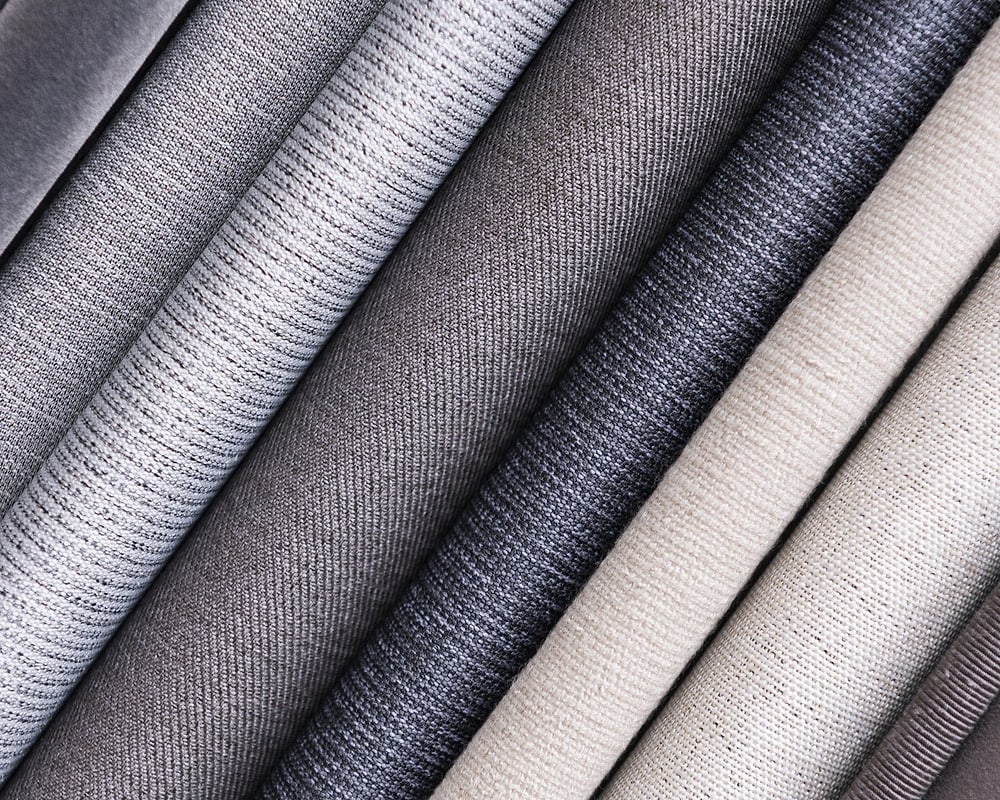 Tessuti d'arredo arrotolati, nelle tonalità del grigio e del beige